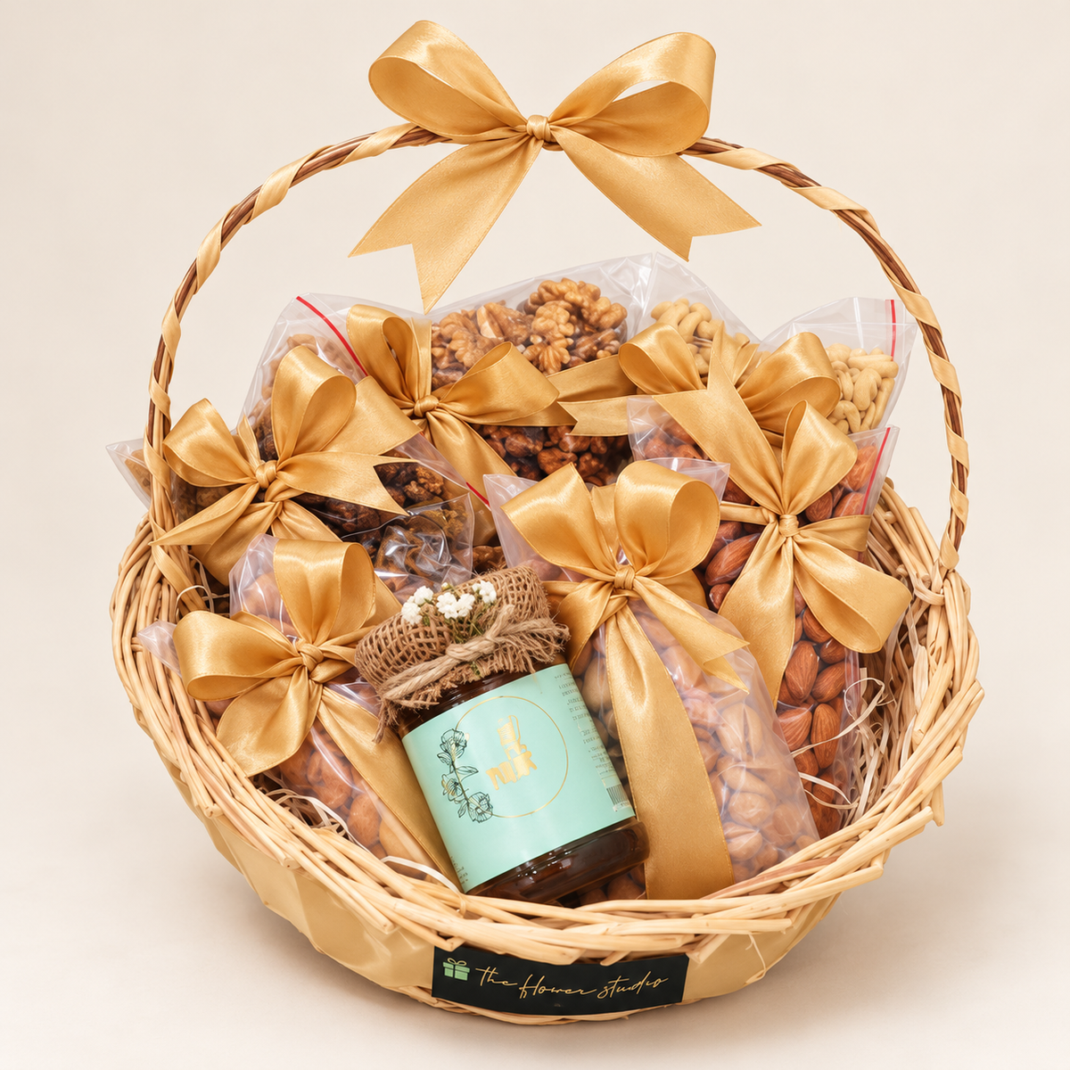 Assorted dry fruit gift basket with a 175g NUR Sidr honey jar, decorated with gold ribbons by The Flower Studio.