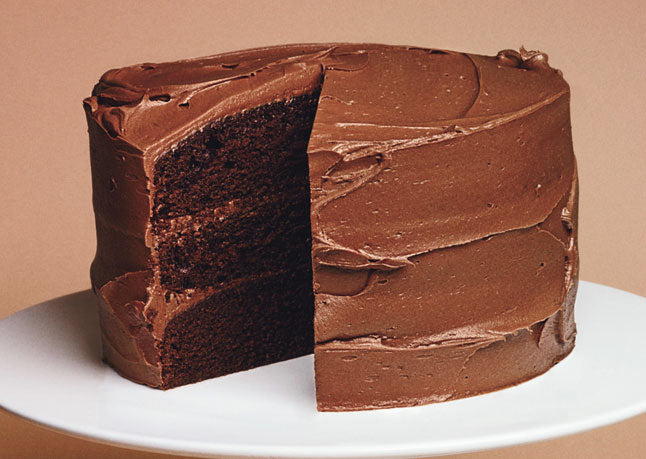 Nando's 4lbs chocolate malt cake with a slice cut out on a white plate against a beige background